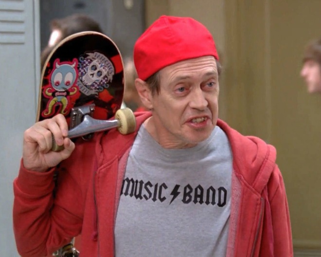 Alter Mann mit Käppi, Skateboard und T-Shirt einer Rockband